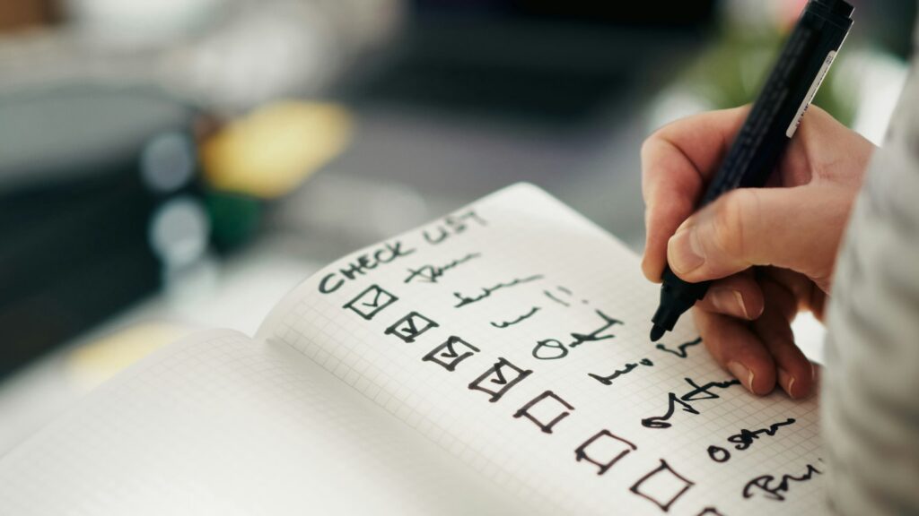 ISO 17025 vs GMP vs ISO 9001: What Lab and Supplier Certifications Mean 1 Close-up of a hand holding a pen and ticking off completed tasks on a checklist in a grid notebook