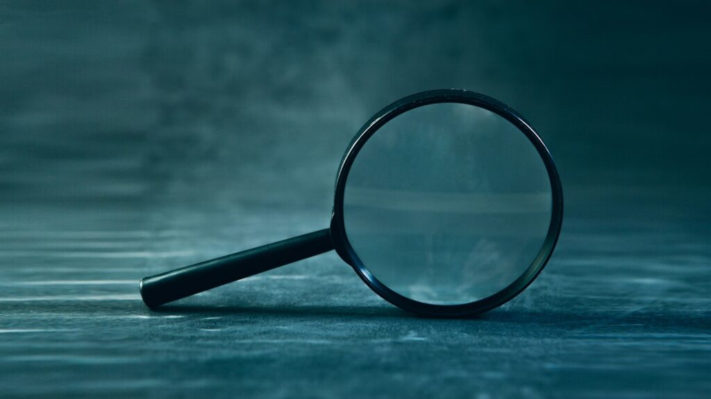 A magnifying glass resting on a dark surface, its lens in sharp focus