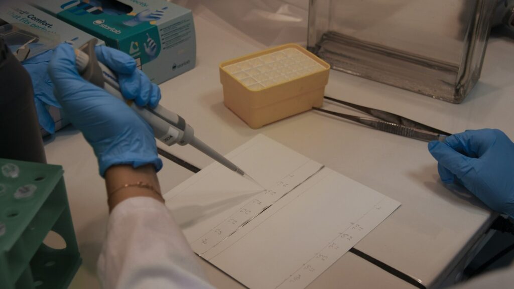 Scientist using a micropipette on a thin-layer chromatography plate