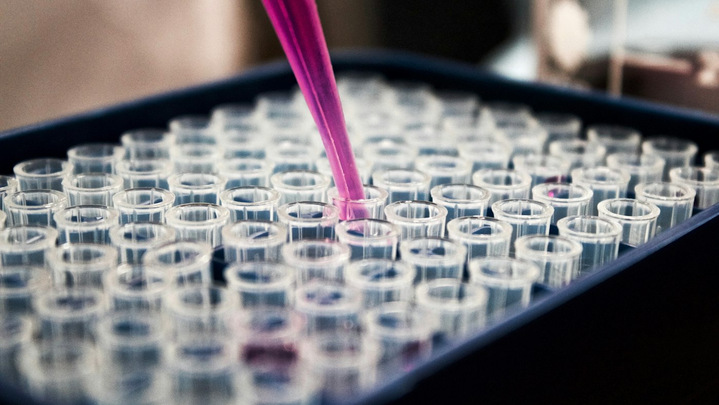 Pipette dispensing liquid into a row of test tubes in a laboratory
