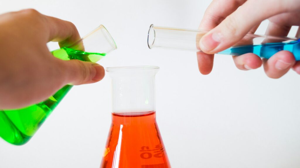 Researcher holding laboratory flasks of coloured liquid