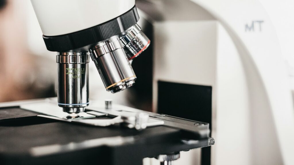 Laboratory microscope with multiple objective lenses above the stage, illustrating mitochondrial peptide research
