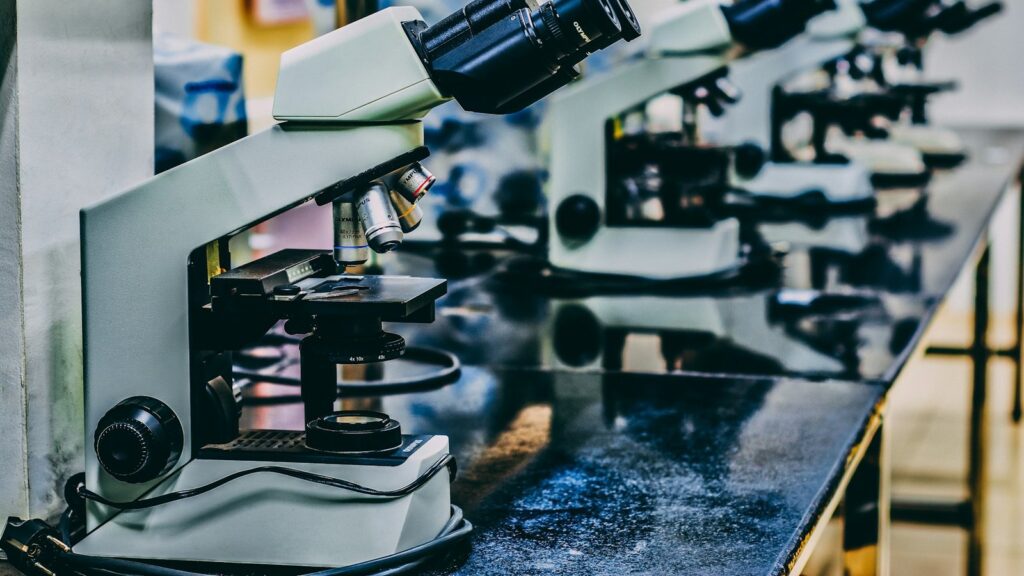 White laboratory microscope on a dark table
