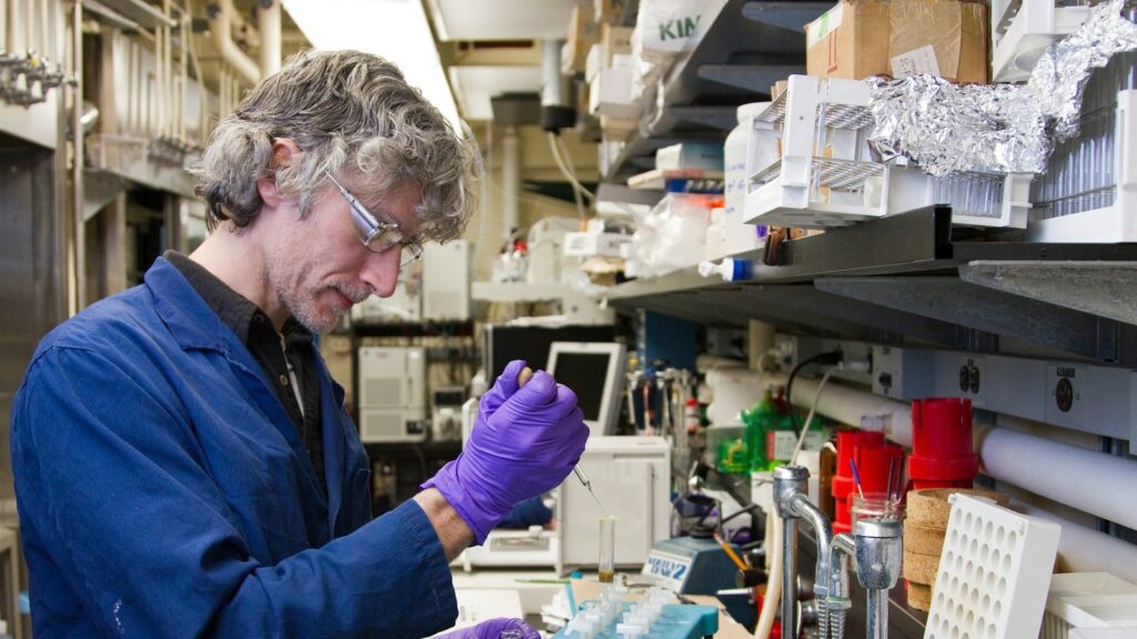 Scientist adding a sample to a test tube with a pipette