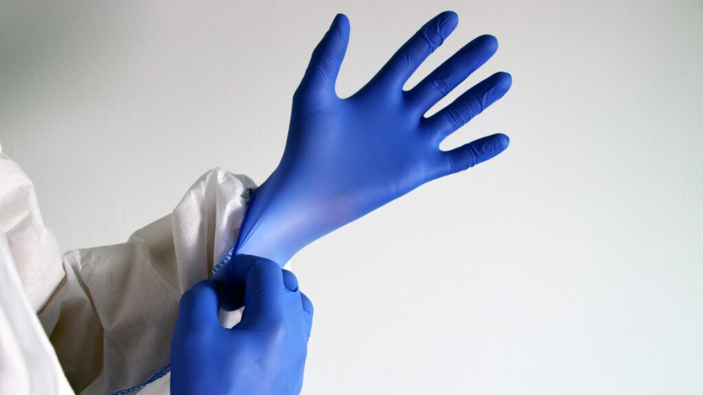 Peptide Lab Safety Under WHMIS: Handling, Spills and Disposal of Peptide Powders 1 Hands pulling on blue nitrile gloves over the sleeve of a white lab coat