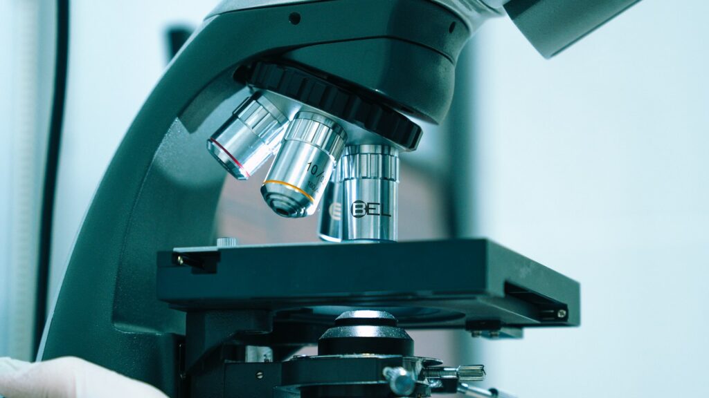 Gloved hand adjusting a laboratory microscope