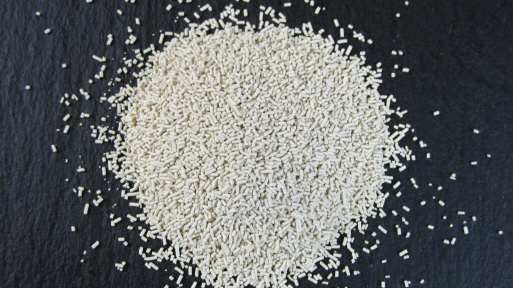 A small pile of dry yeast granules on a black slate board